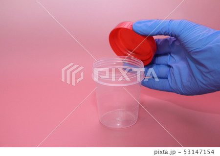 A hand in a blue latex glove holds a container A hand in a blue latex glove holds a container 53147154