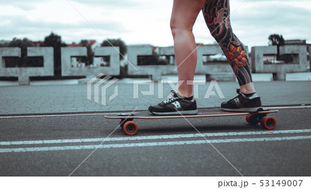 Beautiful young girl with tattoos with longboard 53149007