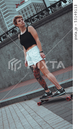 Beautiful young girl with tattoos with longboard 53149113