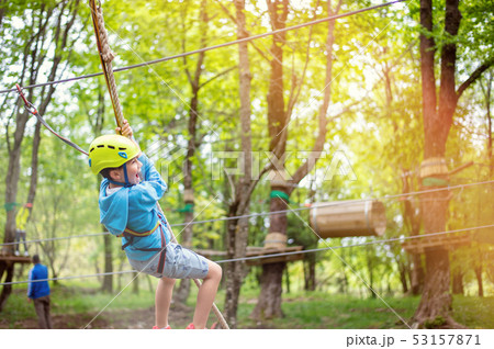 young boy passing cable route among trees, extreme sport in adventure park young boy passing cable route among trees, extreme sport in adventure park 53157871