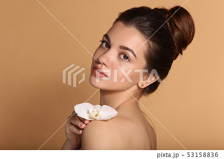Young beautiful girl with flawless skin is holding white orchid flower on her hands. Skin care Young beautiful girl with flawless skin is holding white orchid flower on her hands. Skin care 53158836