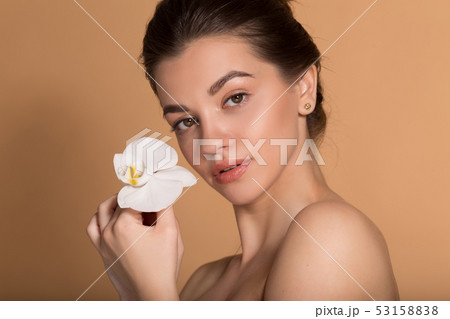 Young beautiful girl with flawless skin is holding white orchid flower on her hands. Skin care Young beautiful girl with flawless skin is holding white orchid flower on her hands. Skin care 53158838