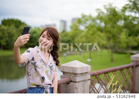 Young beautiful Asian tourist woman relaxing at the park Young beautiful Asian tourist woman relaxing at the park 53162948