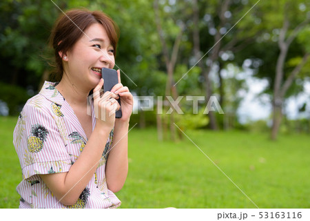 Young beautiful Asian tourist woman relaxing at the park Young beautiful Asian tourist woman relaxing at the park 53163116