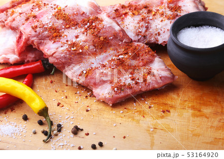 Raw Ribs on a rustic cutting board with salt, pepper and grinder for spices . copy space. Top View. Raw Ribs on a rustic cutting board with salt, pepper and grinder for spices . copy space. Top View. 53164920