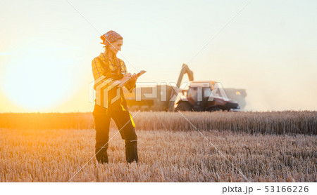 Farmer woman and combine harvester on wheat field Farmer woman and combine harvester on wheat field 53166226