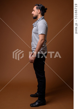 Young bearded Indian man against brown background 53166719