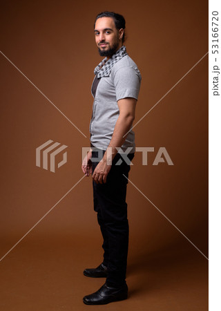 Young bearded Indian man against brown background 53166720