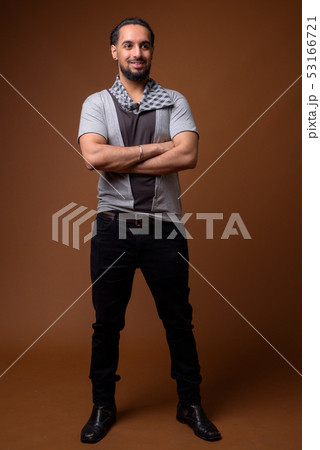 Young bearded Indian man against brown background 53166721