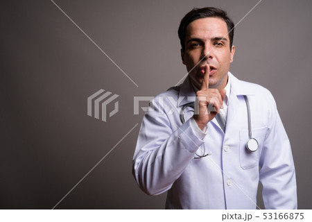 Handsome Persian man doctor against gray background 53166875