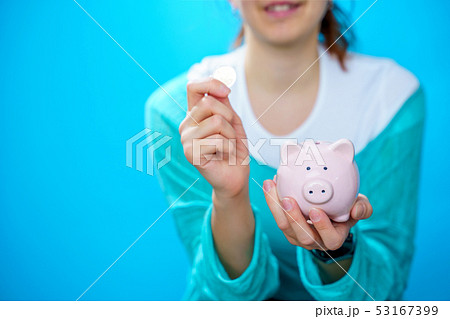 Image of happy woman putting pig in piggy bank Image of happy woman putting pig in piggy bank 53167399