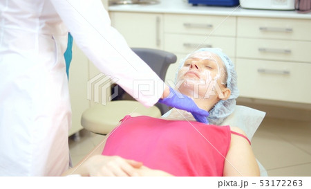 The concept of a beautician. Beautician puts the cream on the girl's face 53172263