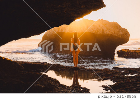 Slim woman posing near ocean with rocks and sunset 53178958