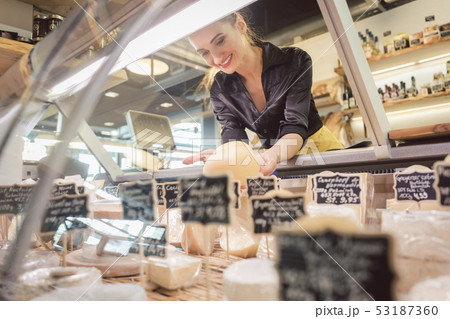 Shop clerk woman sorting cheese in the supermarket display 53187360