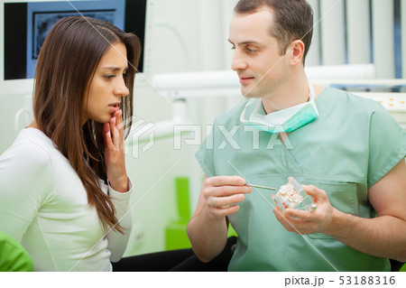 Dentist in dental office talking with female patient and preparing for treatment 53188316