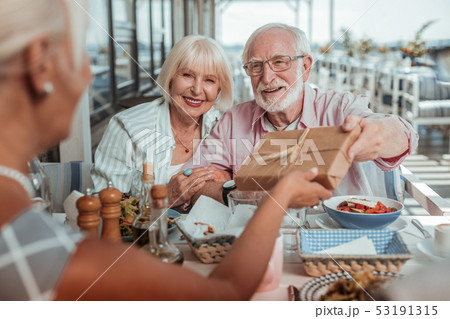 Positive delighted couple giving present to their daughter 53191315