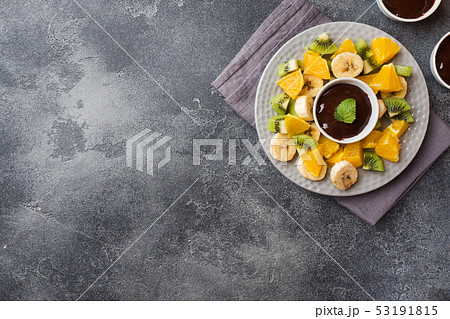 Chocolate fondue with fruit on a dark concrete Chocolate fondue with fruit on a dark concrete 53191815