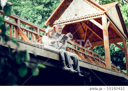Merry couple in years wearing white clothes enjoying a book Merry couple in years wearing white clothes enjoying a book 53192432