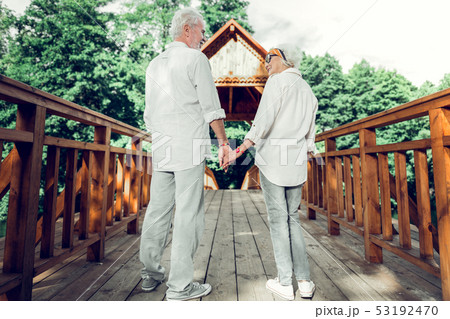 Happy couple holding hands and standing on the bridge. Happy couple holding hands and standing on the bridge. 53192470