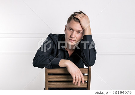 Pensive young handsome man in black shirt sitting 53194079