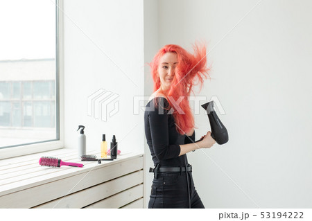 Hairdresser, stylist and people concept - young woman drying her red hair indoors 53194222