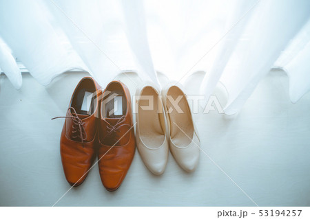 Couple's shoes are placed on ground. 53194257