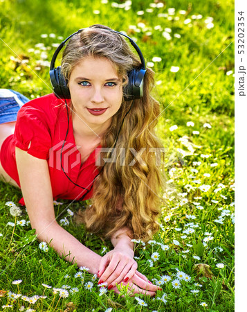 Girl in headphones catch rhythm music on green grass Girl in headphones catch rhythm music on green grass 53202354