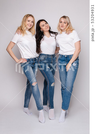 Three beautiful women in white shirts and jeans - Stock Photo