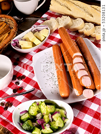 Sausage portion with baguette on table setting on checkered cloth Sausage portion with baguette on table setting on checkered cloth 53208131