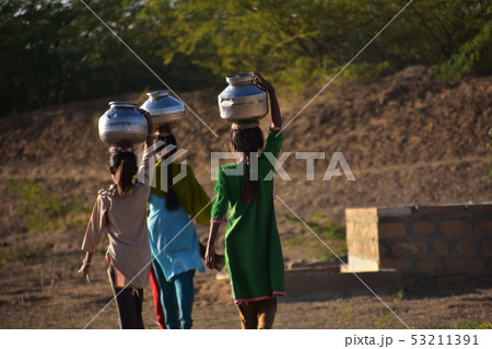 インドのジャイサルメールのクーリー村　民族衣装のサリーを着た美しい女性達　井戸水を頭に乗せて運ぶ姿 53211391
