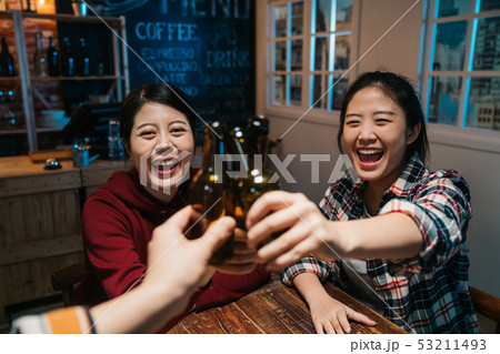 three female friends clinking bottles of beer 53211493