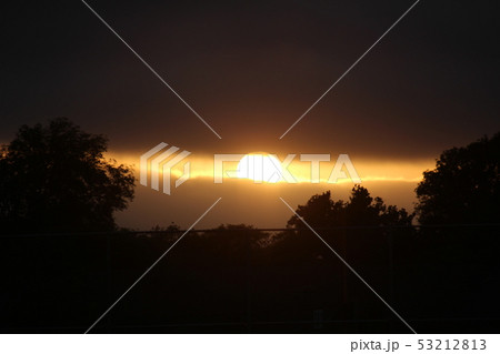 雲に影をひそめる夕陽の写真素材