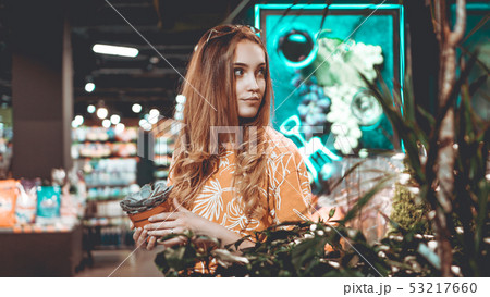 Young woman buying flowers at a garden center Young woman buying flowers at a garden center 53217660