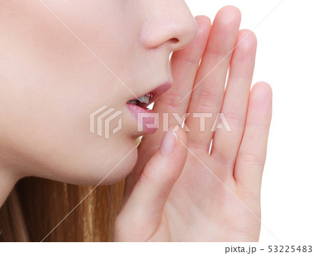 Young blonde woman whispering with hand near mouth Young blonde woman whispering with hand near mouth 53225483