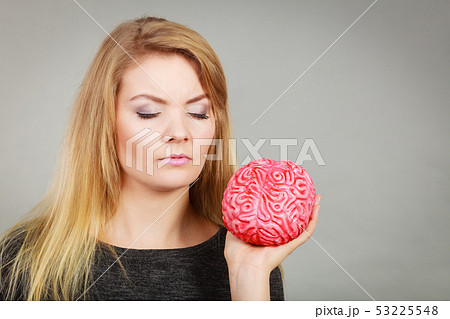 Woman thinking and holding fake brain Woman thinking and holding fake brain 53225548