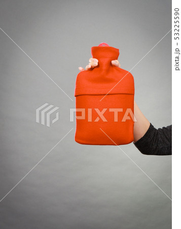 Woman holds hot water bottle in red fleece cover 53225590