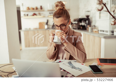 Fashion designer drinking coffee at her workplace. Fashion designer drinking coffee at her workplace. 53227466