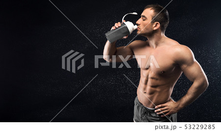 Young sporty man drinking energy cocktail in studio Young sporty man drinking energy cocktail in studio 53229285