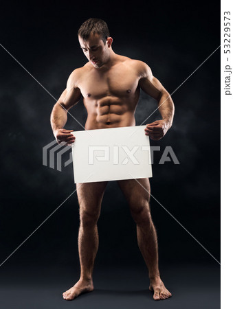 Young naked man with muscular torso holding blank sheet 53229573