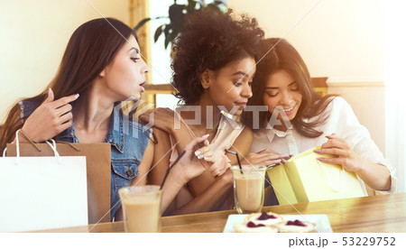 Three female friends sitting in cafe with shopping bags 53229752