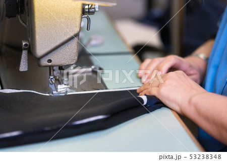 Seamstress sews clothes on a sewing machine. Textile factory. 53238348