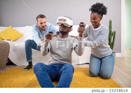 Multiracial group of friends having fun trying on 3D virtual reality goggles. Multiracial group of friends having fun trying on 3D virtual reality goggles. 53258619