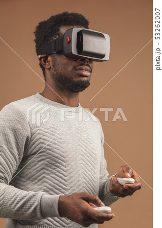 Black man wearing 3d vr glasses, playing videogame, holding joystick in hands 53262007