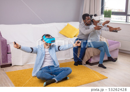 Multiracial group of friends having fun trying on 3D virtual reality goggles. Multiracial group of friends having fun trying on 3D virtual reality goggles. 53262428