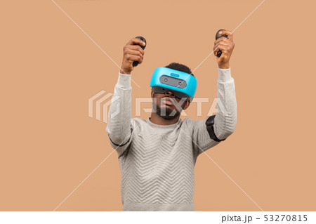Black man wearing 3d vr glasses, playing videogame, holding joystick in hands Black man wearing 3d vr glasses, playing videogame, holding joystick in hands 53270815