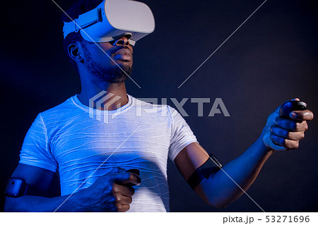 African Man in white, wearing VR Headset on green blue dual color background. 53271696