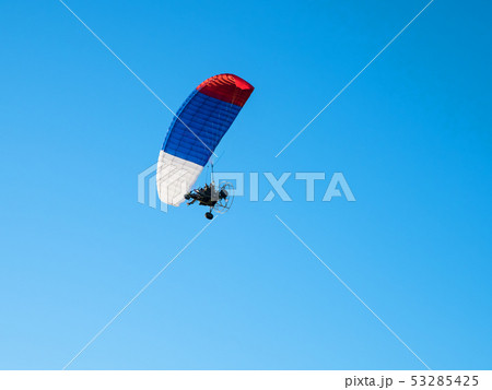 Colorful powered paraglider against blue sky. 53285425