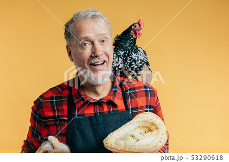 cheerful senior man holding a hat with chickens and a rabbit 53290618