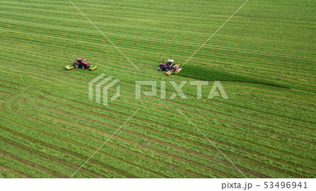 two tractors mows the grass on a green field two tractors mows the grass on a green field 53496941