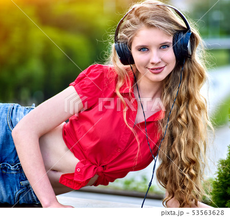 Student girl with backpack headphone listen music on green grass 53563628
